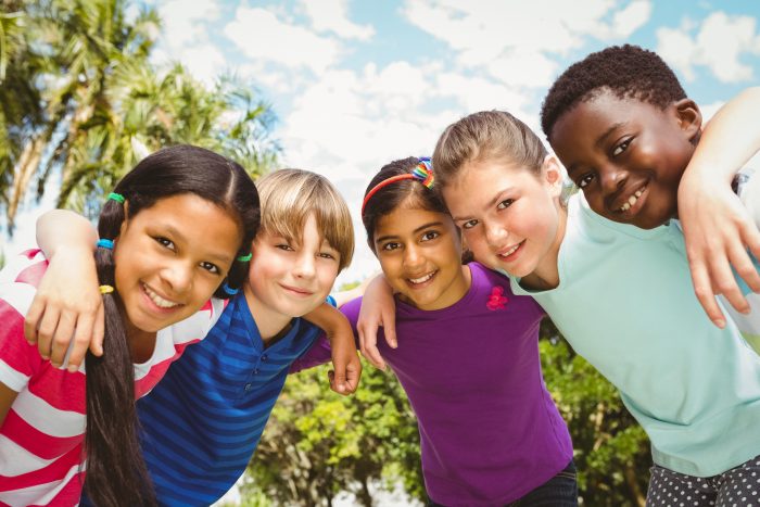 Portrait of happy children forming huddle at the park